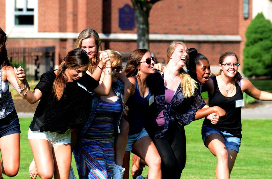 一群女学生在参加校园草坪上的迎新活动时手拉手